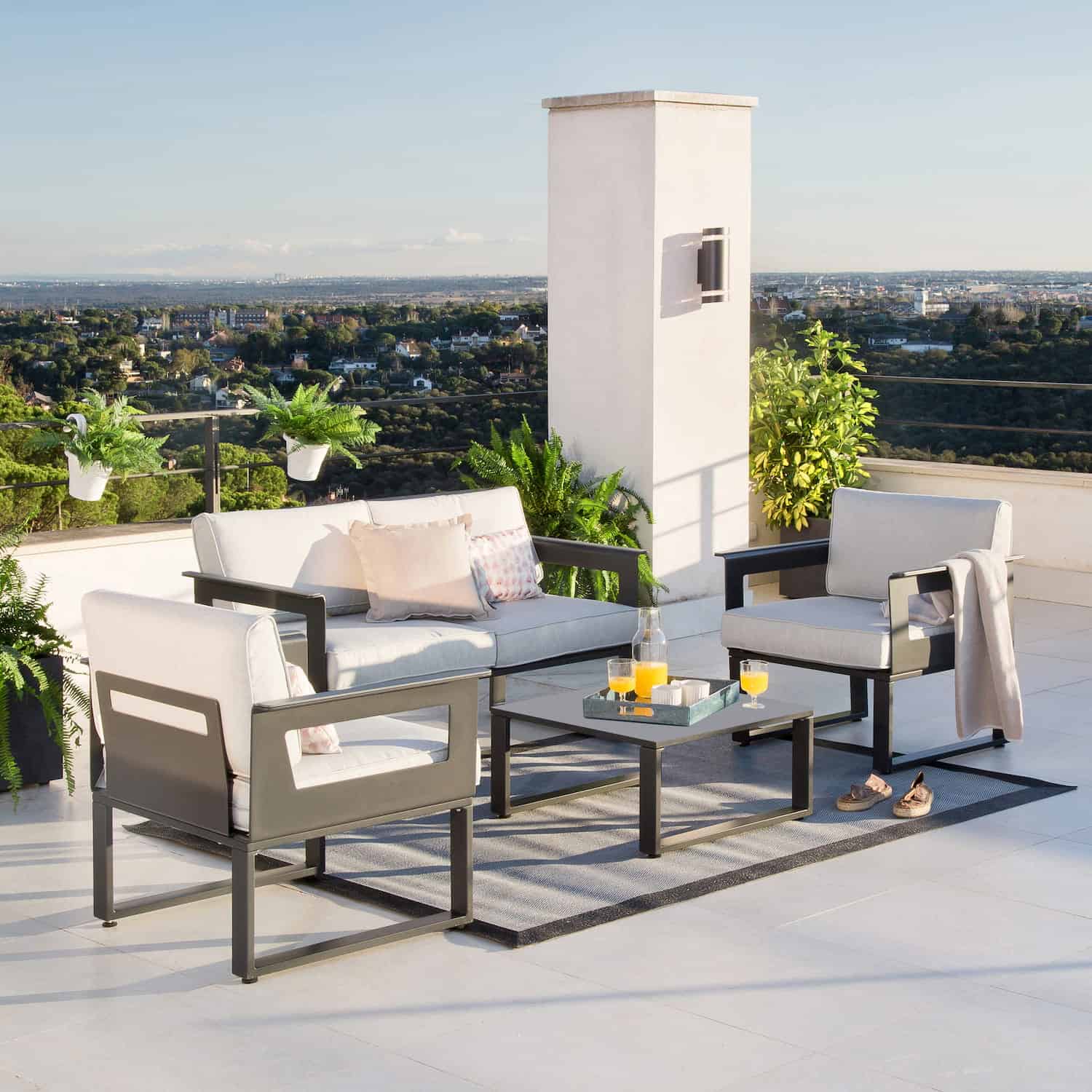 Salon de jardin avec canapé et fauteuils en extérieur sur terrasse.