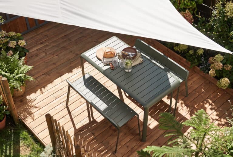 Espace extérieur avec parasol, fauteuils et plantes pour ombrager une terrasse.