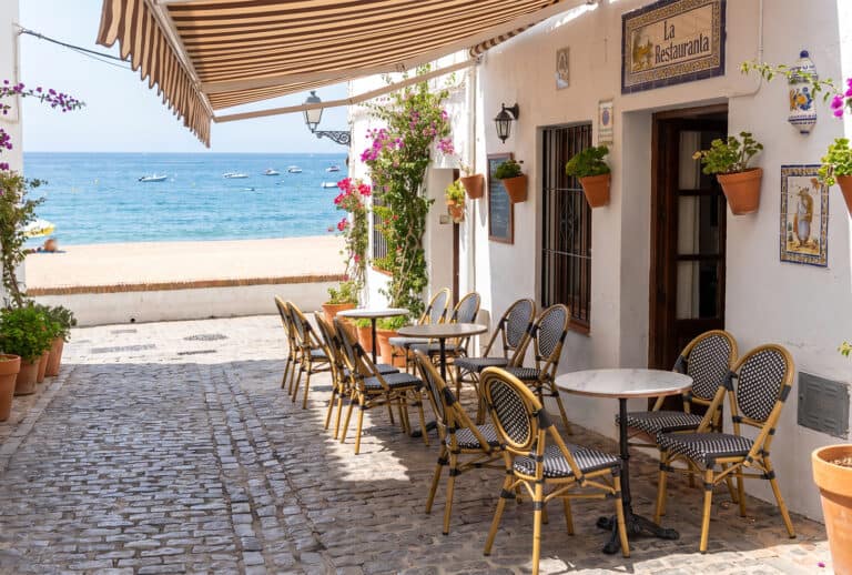 Terrasse de café avec tables et chaises face à la mer.